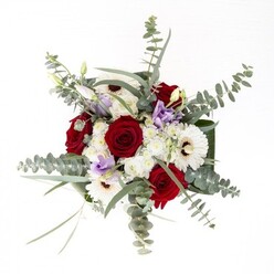 Created with the care and discernment that characterises Downe's finest florists, this bouquet presents a harmonious balance of colour, scent, and form, poised in a clear glass vase that anchors the arrangement in crisp modernity. The ensemble begins with striking red roses at its heart, blooming with artistry and conveying messages of affection, framed by spacious white gerberas whose dark, coffee-hued centers lend contrast and intrigue. Wisps of soft lavender lisianthus thread through the bouquet, some in graceful bud, evoking the dewy promise of a local spring morning. Billowing white filler flowers nestle between the larger blossoms, providing textural interest and a hint of softness. Surrounding all, silvery-green eucalyptus branches infuse gentle fragrance and a contemporary edge, their rounded leaves reminiscent of native Kentish hedgerows. At the base, robust, glossy green leaves are fanned and wrapped, enclosing the stems-with their fresh, clean lines visible through the vase-giving the design a sense of artistry and refinement. Whether chosen to celebrate an anniversary, welcome a loved one home in Downe, or simply to savour the luxury of fresh flowers, this bouquet embodies the village's sense of understated sophistication and the florist's pride in hand-crafted beauty.